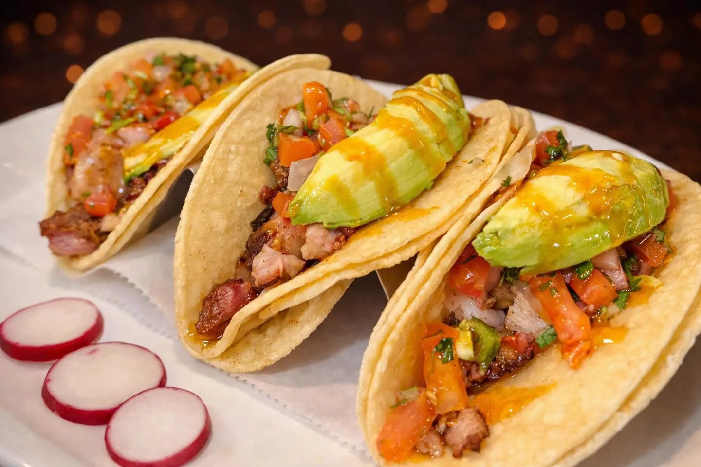 Street tacos topped with avocado, pico de gallo and radish